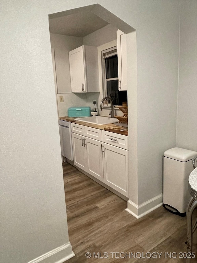 kitchen with dishwasher, sink, dark wood-type flooring, and white cabinets