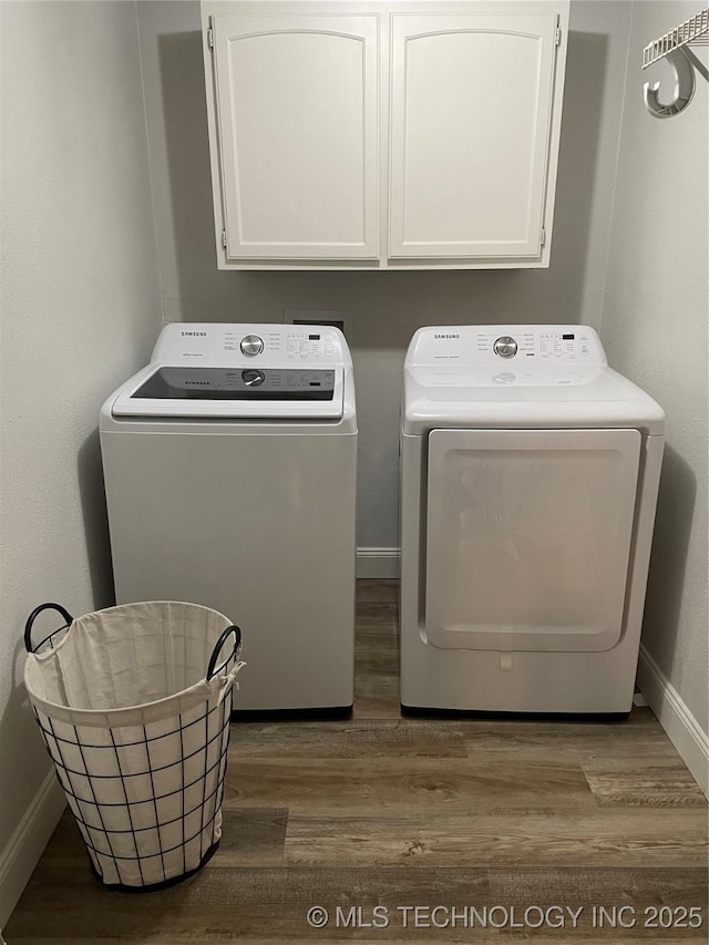 laundry room with dark hardwood / wood-style flooring, cabinets, and washing machine and clothes dryer