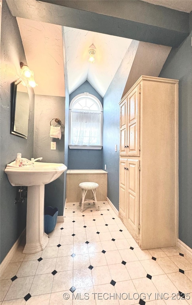 bathroom featuring lofted ceiling and tile patterned flooring