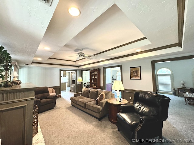 carpeted living room with a tray ceiling and ceiling fan