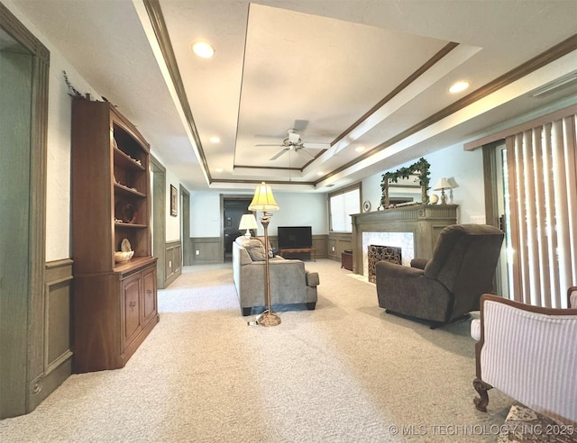 carpeted living room featuring a raised ceiling, a premium fireplace, and ceiling fan