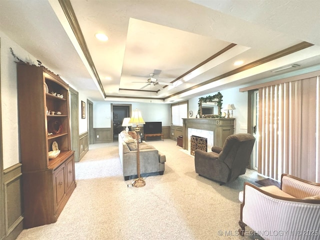 carpeted living room featuring ornamental molding, ceiling fan, and a tray ceiling