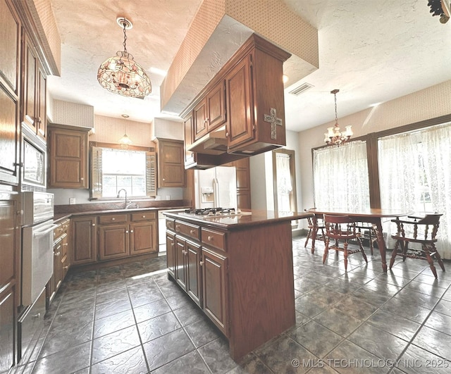 kitchen with decorative light fixtures, sink, a notable chandelier, a tray ceiling, and stainless steel appliances