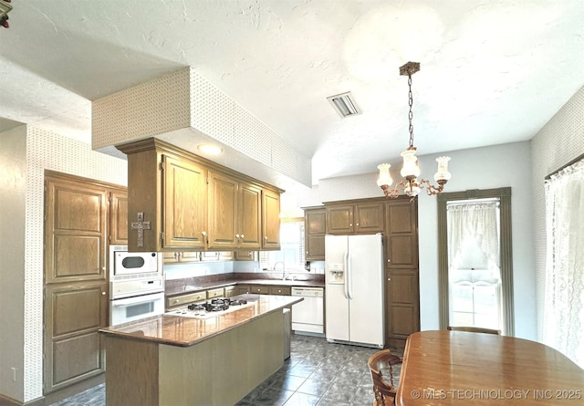 kitchen with pendant lighting, sink, white appliances, an inviting chandelier, and a kitchen island