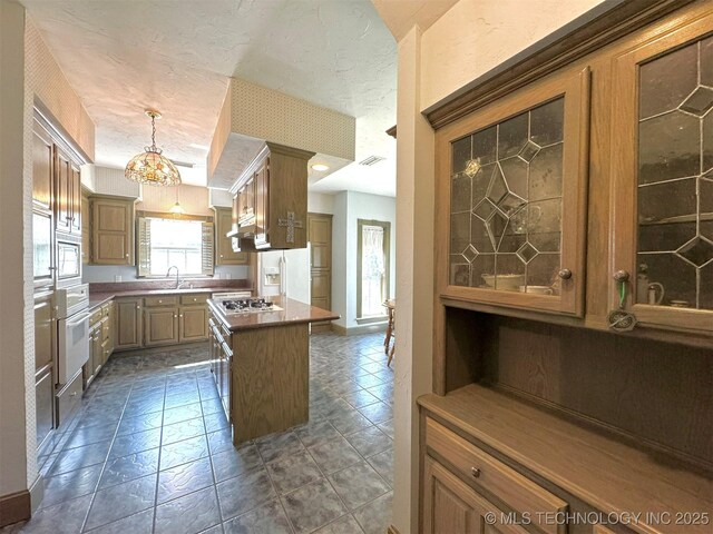 kitchen with white appliances, decorative light fixtures, a center island, and sink