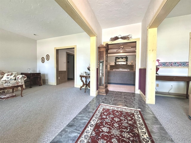 hallway with dark carpet and a textured ceiling