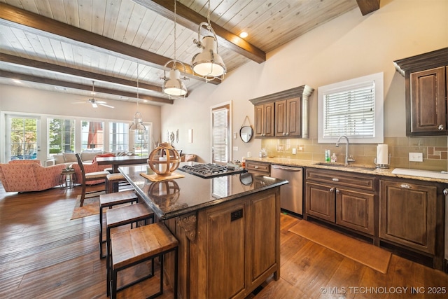 kitchen with sink, backsplash, stainless steel appliances, a center island, and stone countertops