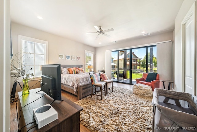 bedroom featuring multiple windows, hardwood / wood-style flooring, access to exterior, and ceiling fan