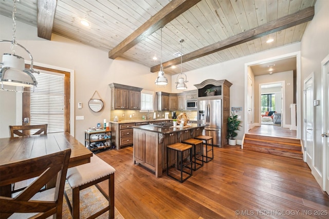 kitchen with beam ceiling, stainless steel appliances, a center island, tasteful backsplash, and wooden ceiling