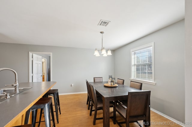 dining area with sink, light hardwood / wood-style flooring, and a notable chandelier