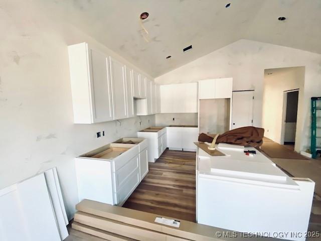 kitchen with lofted ceiling, dark hardwood / wood-style floors, a center island, and white cabinets