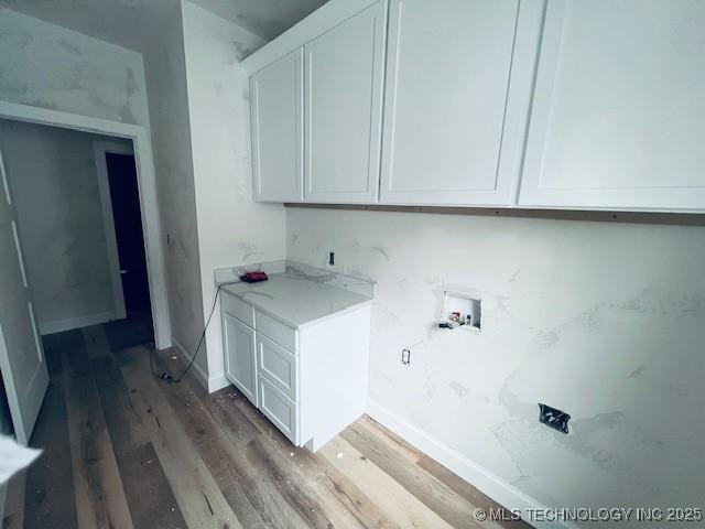 washroom with hardwood / wood-style floors, hookup for a washing machine, and cabinets