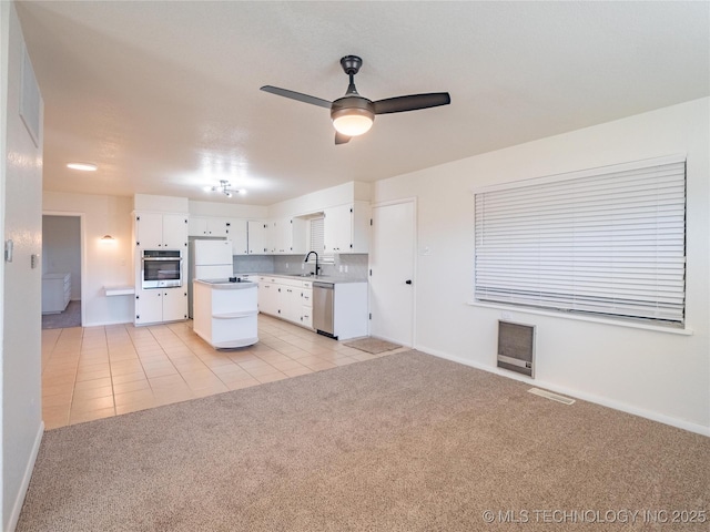 kitchen with appliances with stainless steel finishes, sink, light colored carpet, and white cabinets