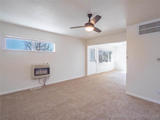 carpeted empty room featuring heating unit and ceiling fan