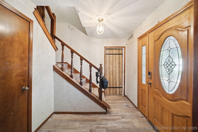 entryway with light hardwood / wood-style flooring and a textured ceiling