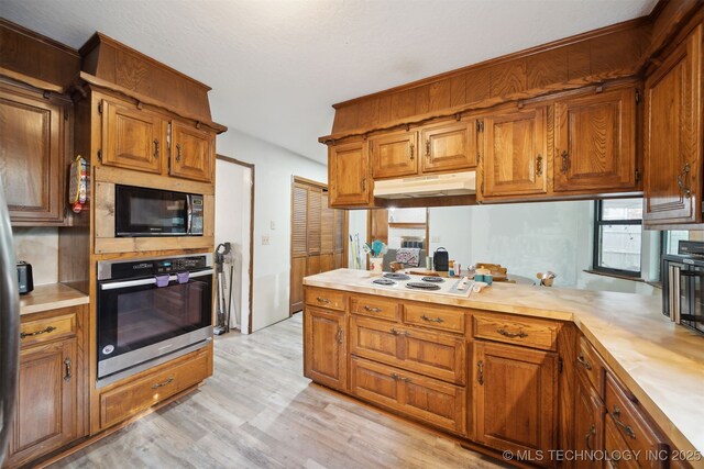 kitchen featuring white stovetop, stainless steel oven, and light hardwood / wood-style floors