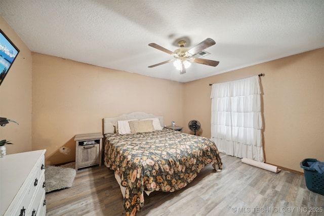 bedroom with a textured ceiling, light hardwood / wood-style floors, and ceiling fan