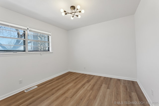 spare room featuring an inviting chandelier and hardwood / wood-style flooring