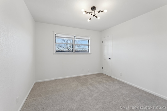 carpeted spare room featuring a chandelier