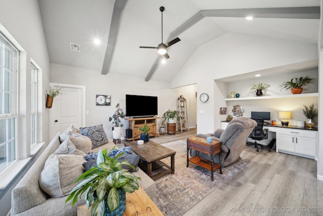 living room featuring ceiling fan, built in desk, lofted ceiling with beams, and light wood-type flooring