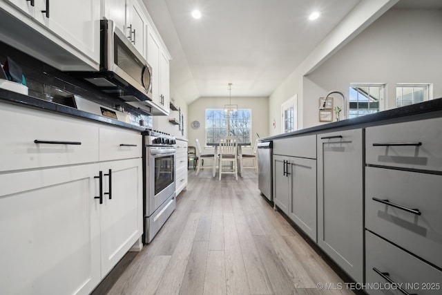 kitchen with white cabinetry, decorative light fixtures, light hardwood / wood-style floors, and appliances with stainless steel finishes