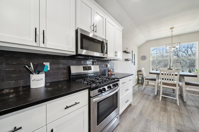 kitchen featuring tasteful backsplash, lofted ceiling, white cabinets, hanging light fixtures, and stainless steel appliances