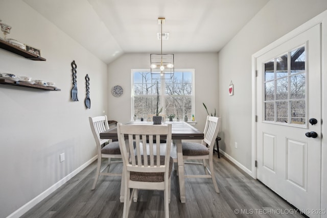 dining space featuring lofted ceiling, dark wood-type flooring, and a chandelier