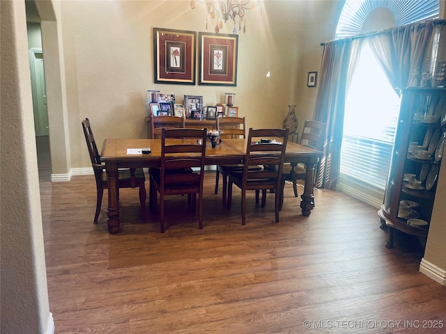 dining area featuring an inviting chandelier, a healthy amount of sunlight, and wood-type flooring