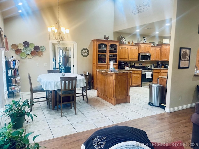 kitchen featuring light stone counters, a chandelier, light tile patterned floors, appliances with stainless steel finishes, and pendant lighting