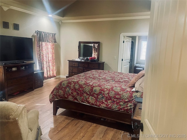 bedroom with crown molding, lofted ceiling, and light hardwood / wood-style floors