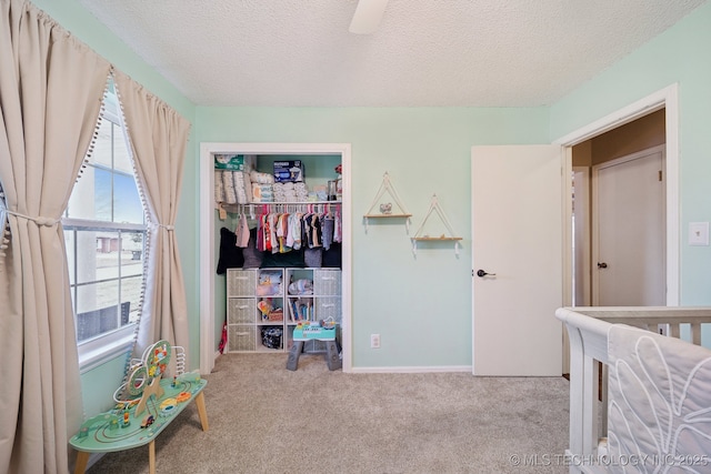 bedroom featuring baseboards, ceiling fan, a closet, a textured ceiling, and carpet flooring