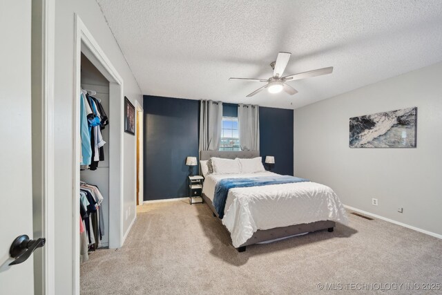 carpeted bedroom featuring a crib, a textured ceiling, and ceiling fan