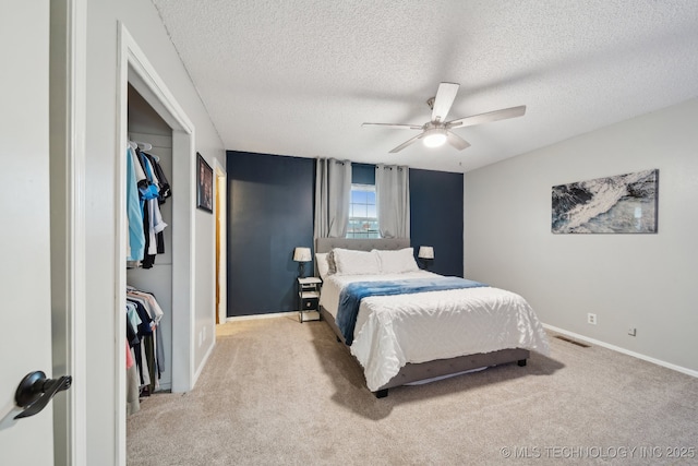 carpeted bedroom featuring a ceiling fan, baseboards, visible vents, a closet, and a textured ceiling