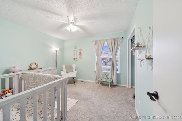 bedroom with visible vents, a crib, baseboards, light colored carpet, and a textured ceiling