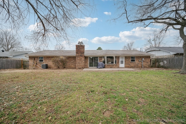 back of property featuring brick siding, a patio, a fenced backyard, and a lawn