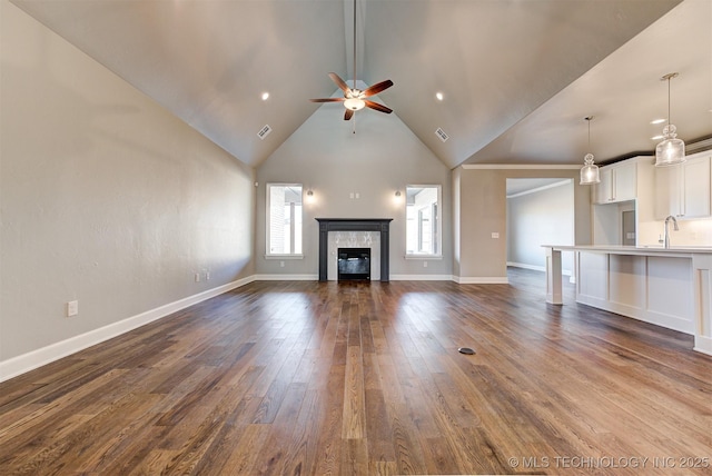 unfurnished living room with a fireplace, lofted ceiling, sink, dark hardwood / wood-style flooring, and ceiling fan