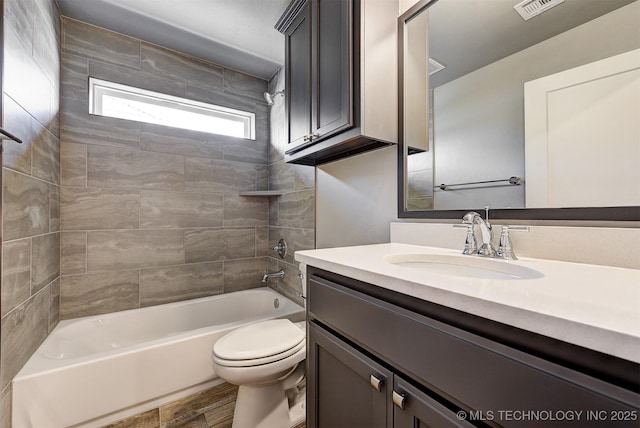 full bathroom featuring tiled shower / bath combo, vanity, hardwood / wood-style floors, and toilet