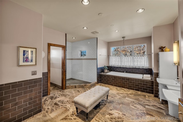 bathroom with tile walls and a relaxing tiled tub