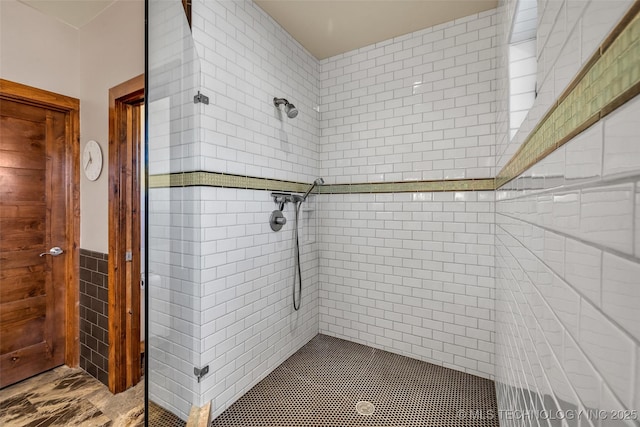 bathroom with tiled shower and tile walls