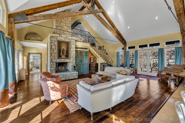 living room with a stone fireplace, high vaulted ceiling, beamed ceiling, wood-type flooring, and french doors