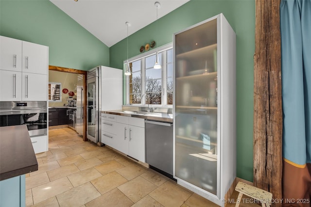 kitchen with sink, appliances with stainless steel finishes, white cabinets, decorative light fixtures, and vaulted ceiling