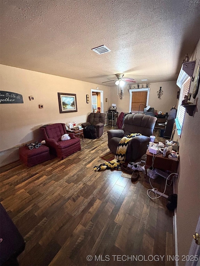 living room with ceiling fan, dark wood-type flooring, and a textured ceiling