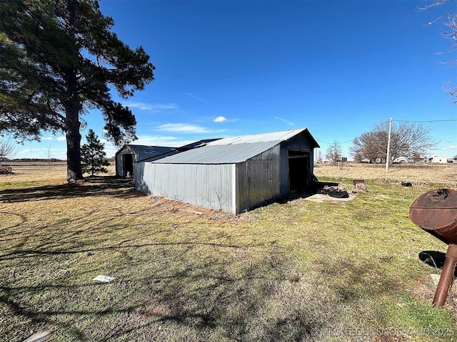 view of outdoor structure with a rural view and a lawn