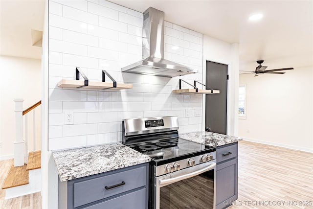 kitchen featuring tasteful backsplash, wall chimney exhaust hood, light stone countertops, and stainless steel range with electric cooktop
