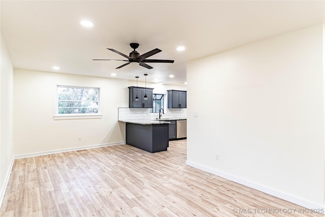 kitchen with tasteful backsplash, dishwasher, light stone counters, and light hardwood / wood-style flooring