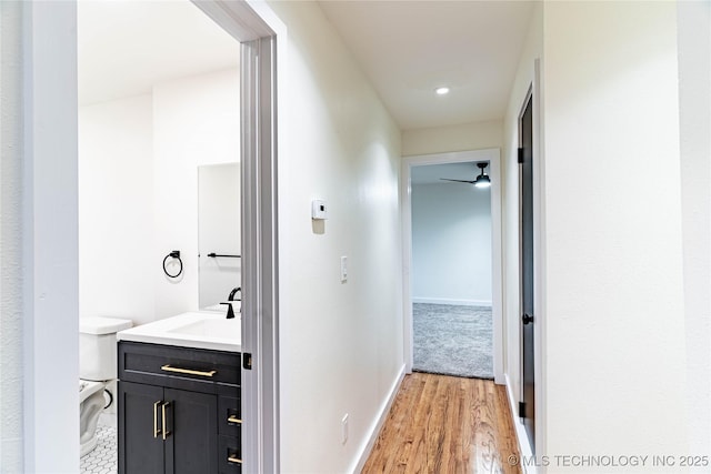 corridor with sink and light hardwood / wood-style flooring