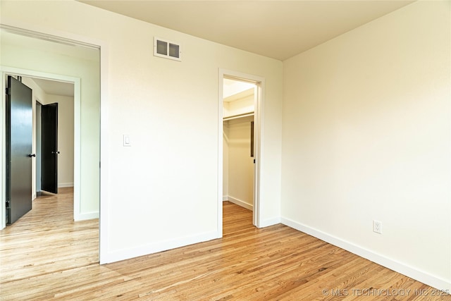 unfurnished bedroom featuring a spacious closet, light hardwood / wood-style floors, and a closet