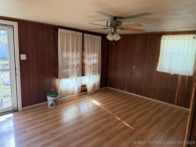 unfurnished room with wooden walls and light wood-type flooring