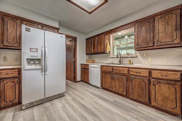 kitchen with sink, dishwasher, white fridge with ice dispenser, a textured ceiling, and light wood-type flooring