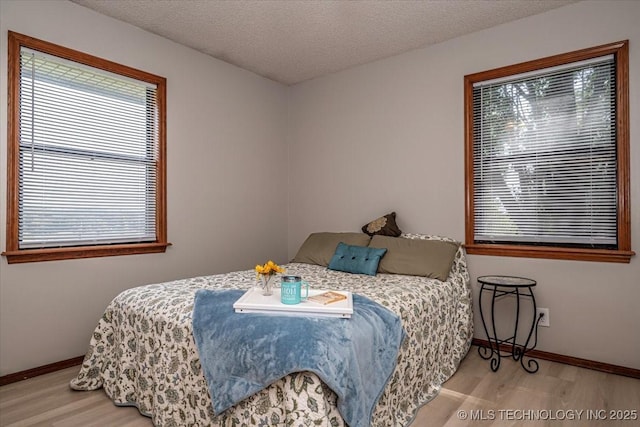 bedroom with a textured ceiling, multiple windows, and light hardwood / wood-style flooring